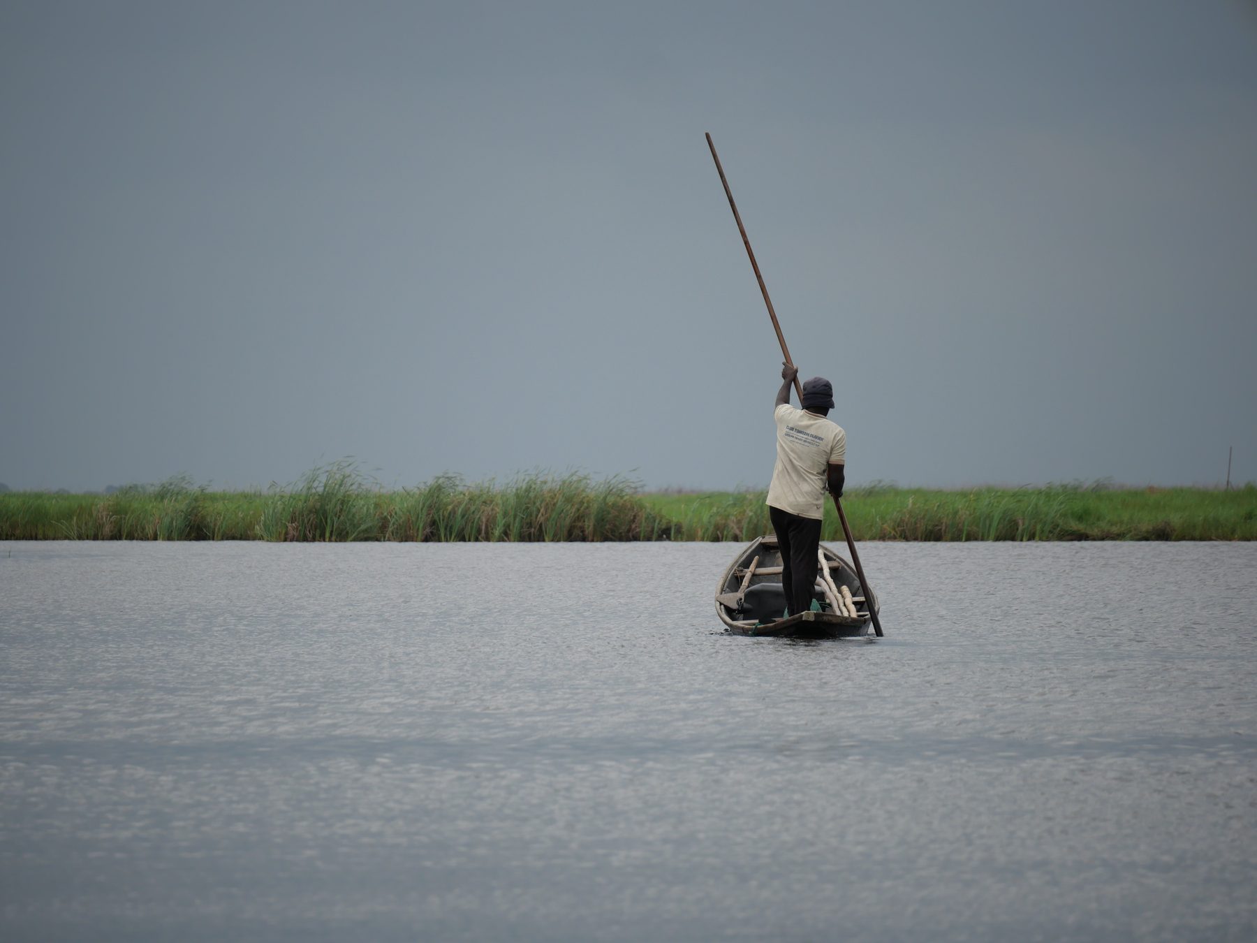 Pêcheur debout sur une pirogue dans la lagune